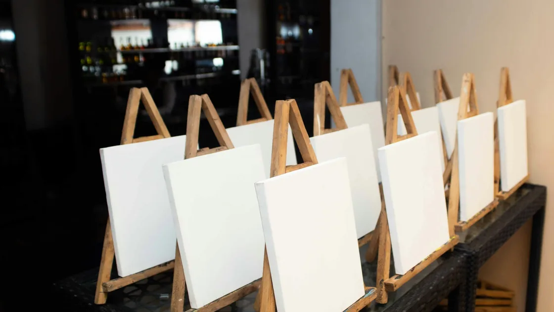 Lienzos blancos montados sobre caballetes de madera alineados en el interior de un taller de pintura